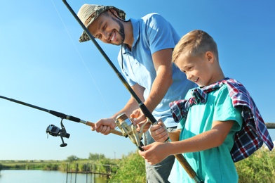 Photo of Father and son fishing together on sunny day