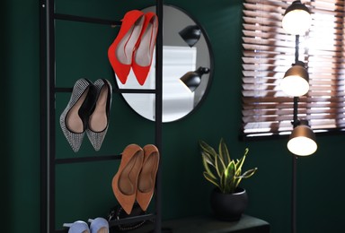 Photo of Storage rack with stylish women's shoes in hallway