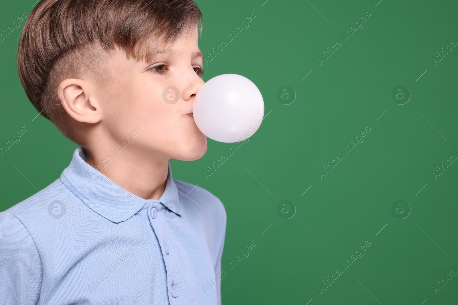 Photo of Boy blowing bubble gum on green background, space for text