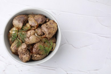 Tasty fried chicken liver with onion and dill in bowl on white textured table, top view. Space for text