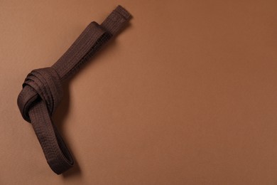 Karate belt on brown background, top view. Space for text