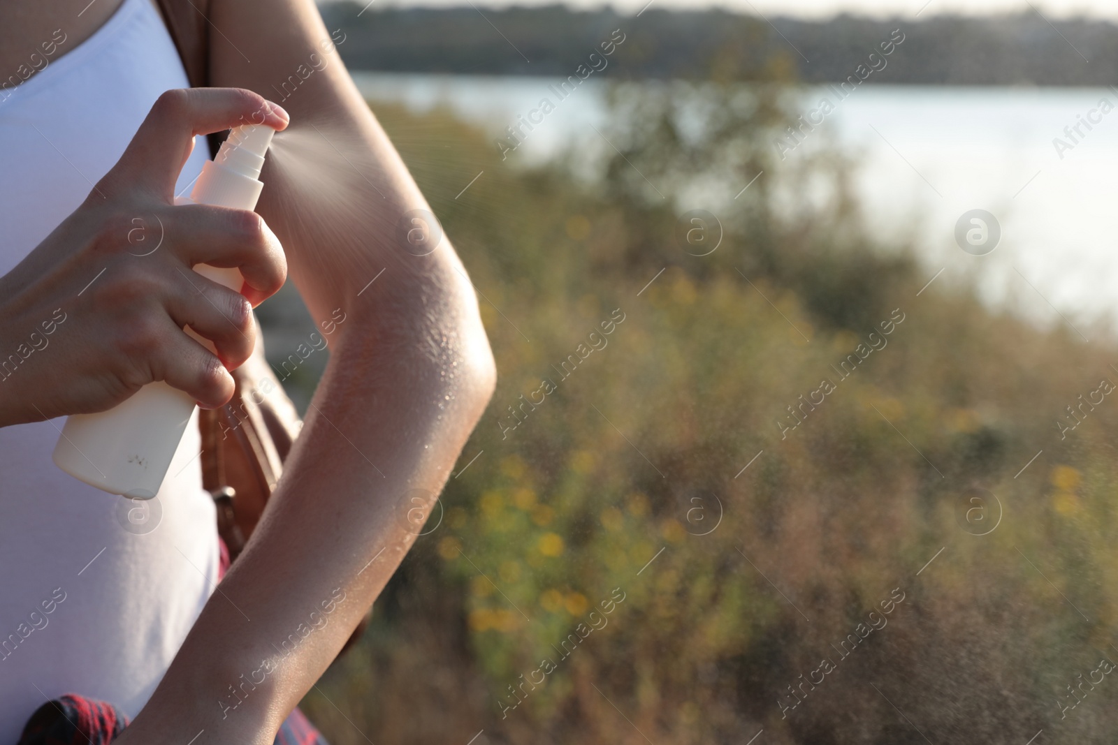 Photo of Woman applying insect repellent onto arm outdoors, closeup. Space for text