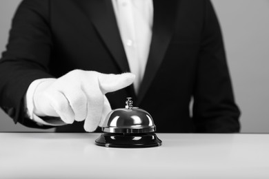 Photo of Butler ringing service bell at white table, closeup