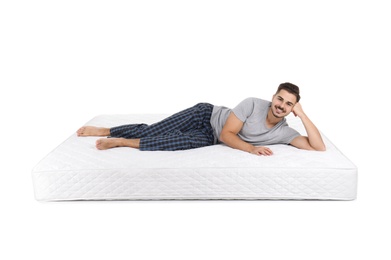 Young man lying on mattress against white background