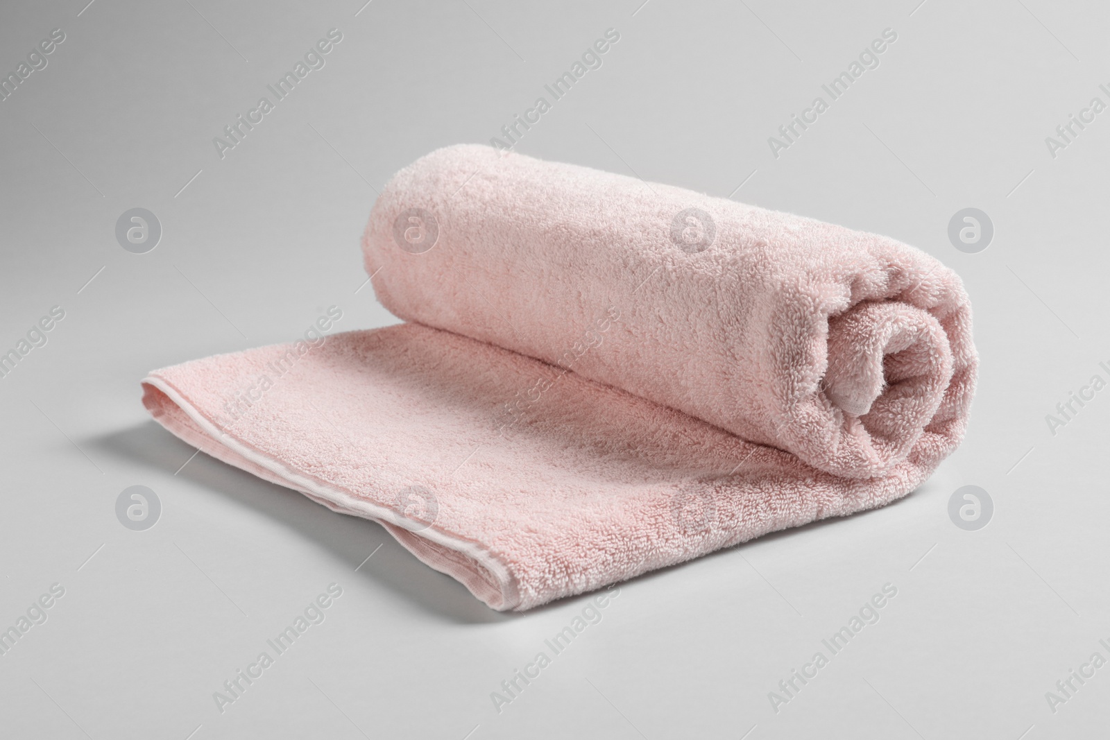 Photo of Fresh soft rolled towel on light background