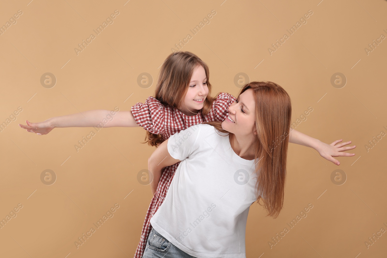 Photo of Happy mother with her cute daughter on beige background