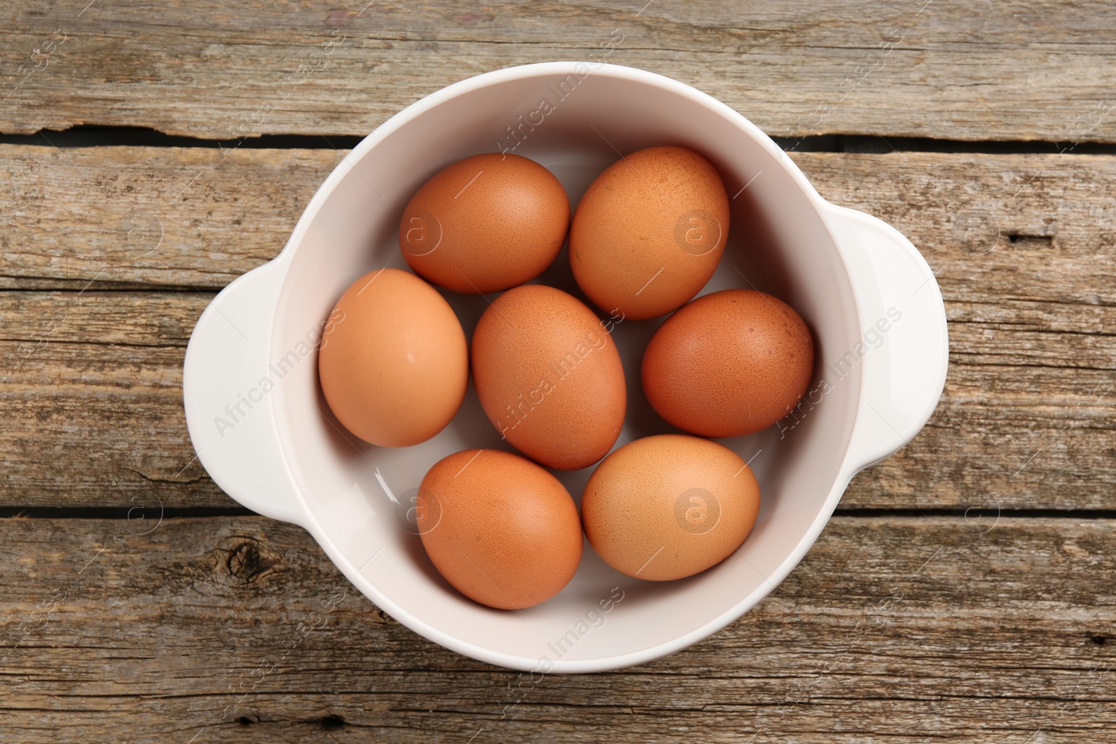 Photo of Unpeeled boiled eggs in saucepan on old wooden table, top view