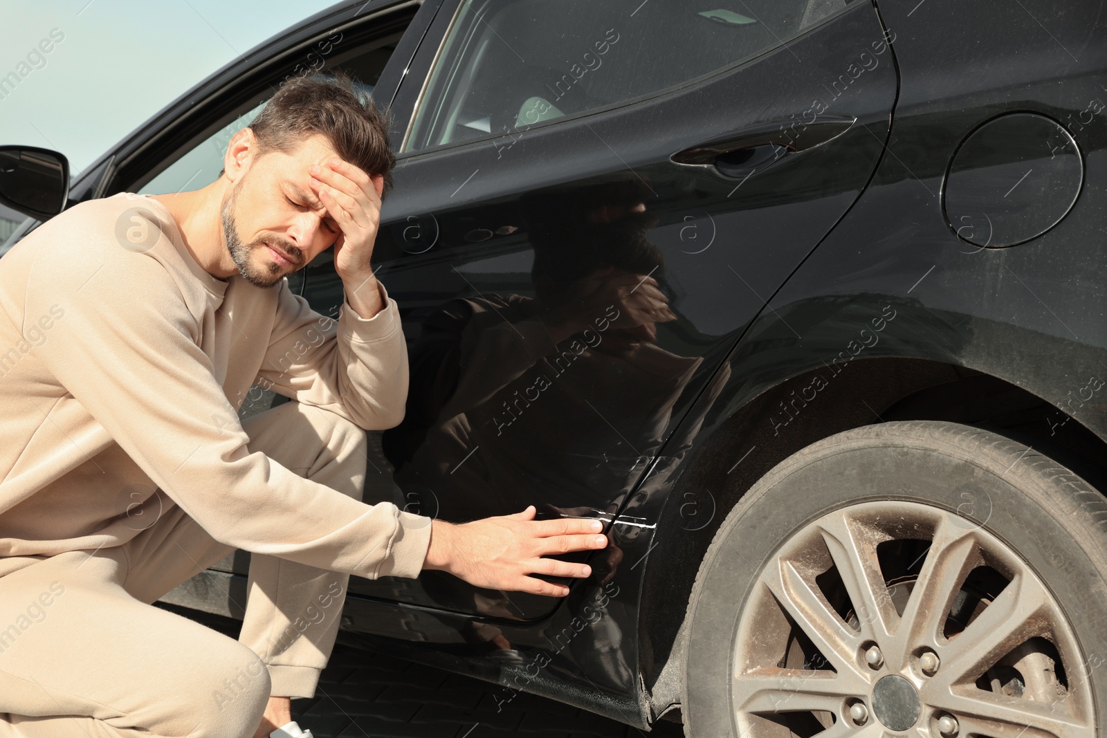 Photo of Stressed man near car with scratch outdoors