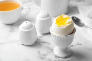 Photo of Holder with soft boiled egg on table. Space for text