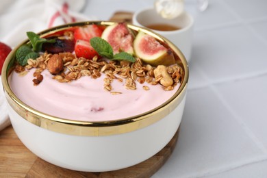 Photo of Bowl with yogurt, fruits and granola on white tiled table, closeup. Space for text