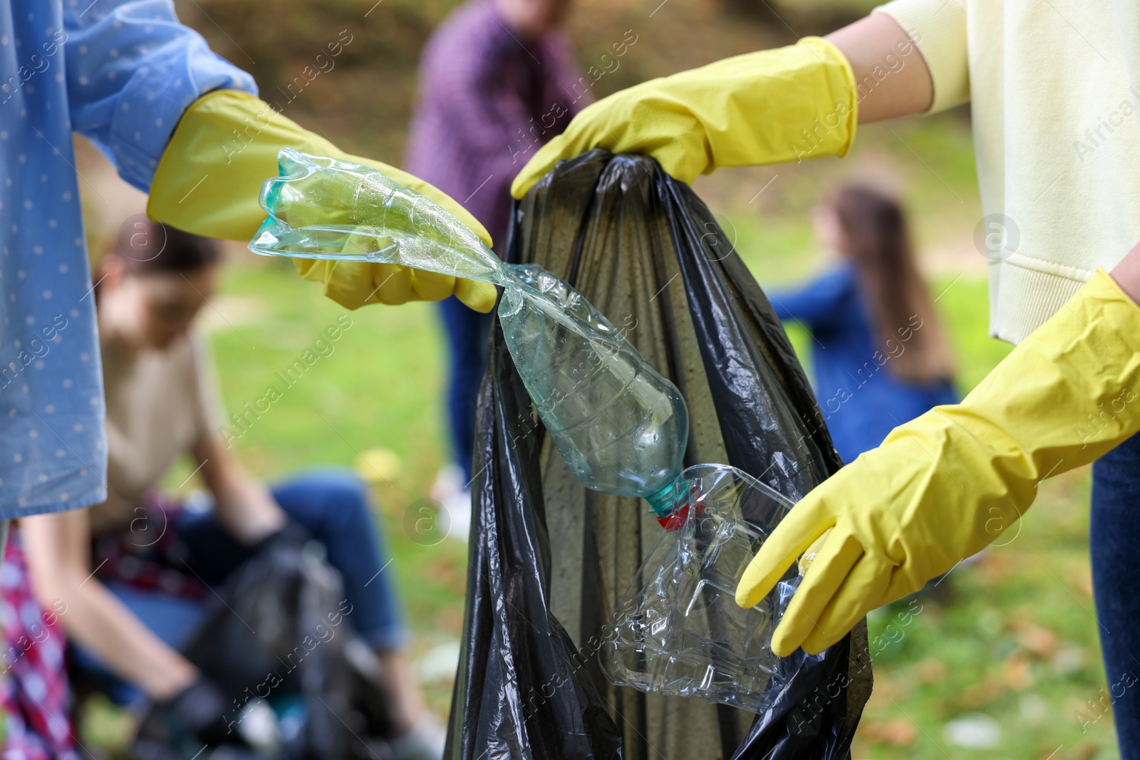 Photo of Women with plastic bag collecting garbage in park, closeup