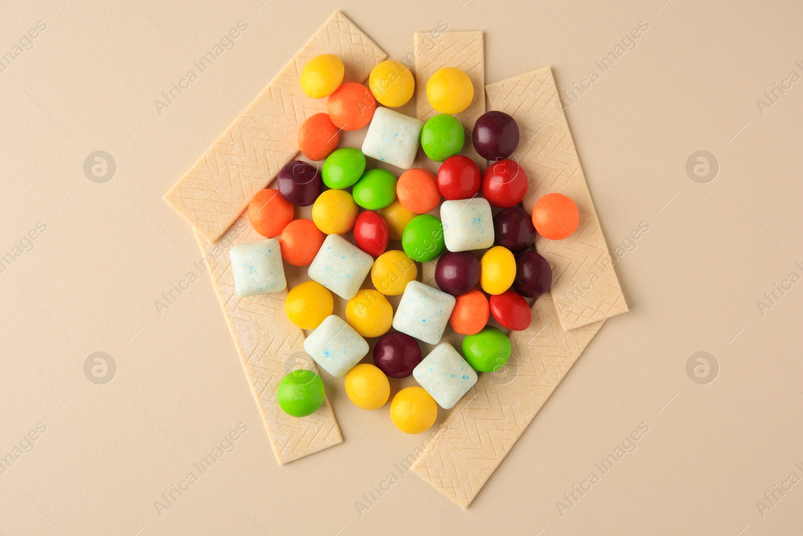Photo of Different tasty chewing gums on beige background, flat lay