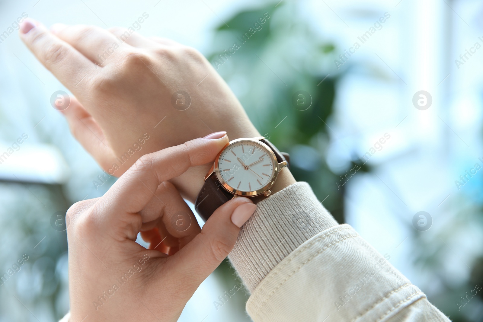 Photo of Woman with luxury wristwatch on blurred background, closeup