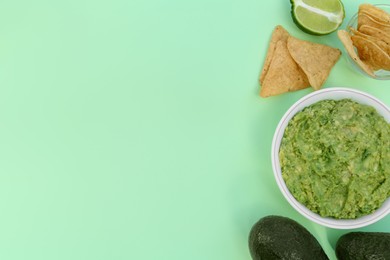 Delicious guacamole, avocados, lime and nachos on light background, flat lay. Space for text