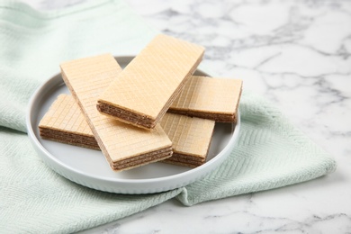 Plate of delicious wafers on marble background