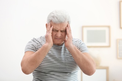 Photo of Mature man suffering from headache at home