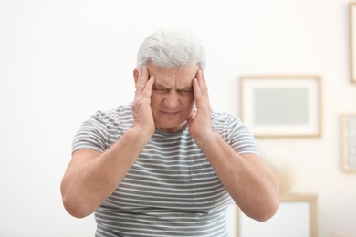 Mature man suffering from headache at home