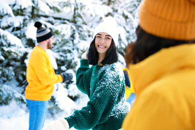 Happy friends playing snowballs outdoors. Winter vacation