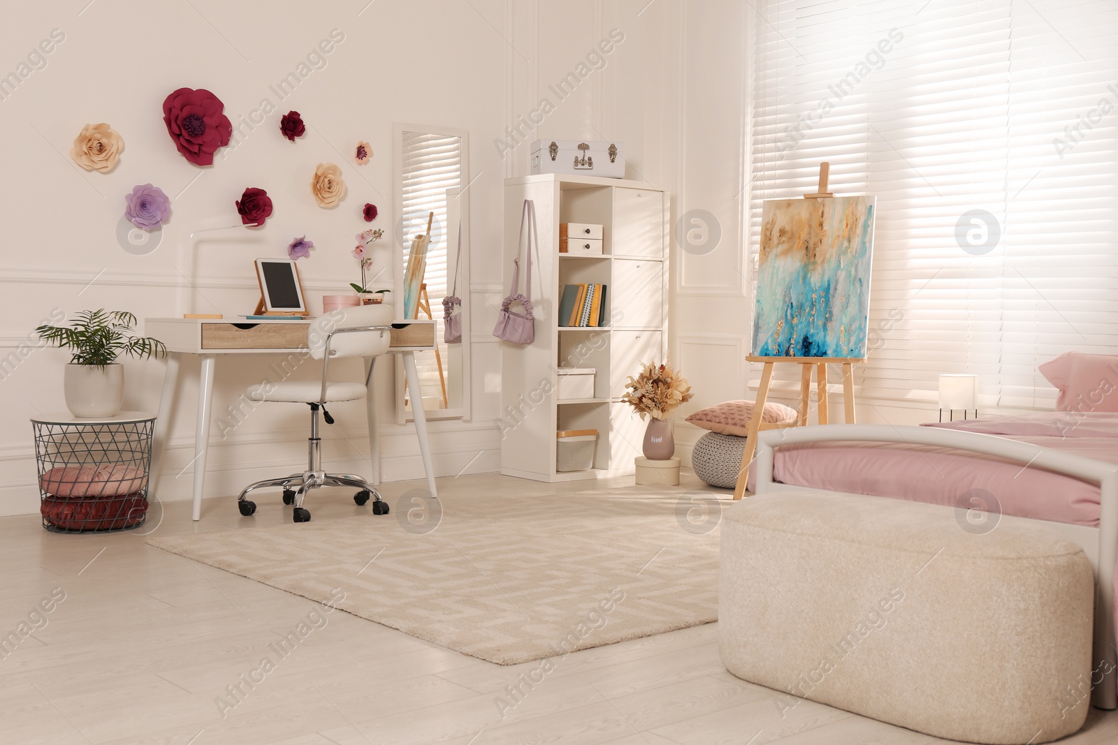 Photo of Stylish teenager's room interior with computer, comfortable bed and painting easel