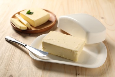 Tasty butter and knife on wooden table