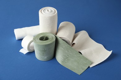 Photo of Medical bandage rolls and sticking plaster on blue background