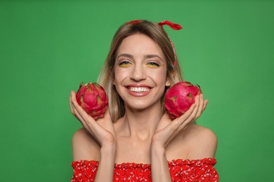 Photo of Young woman with fresh pitahayas on green background. Exotic fruits