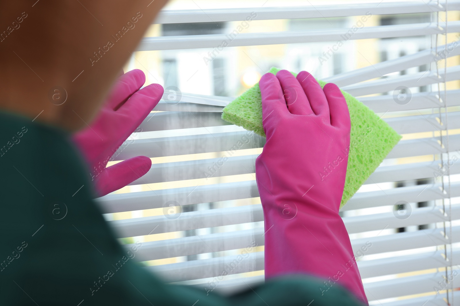 Image of Woman cleaning window blinds with rag indoors, closeup