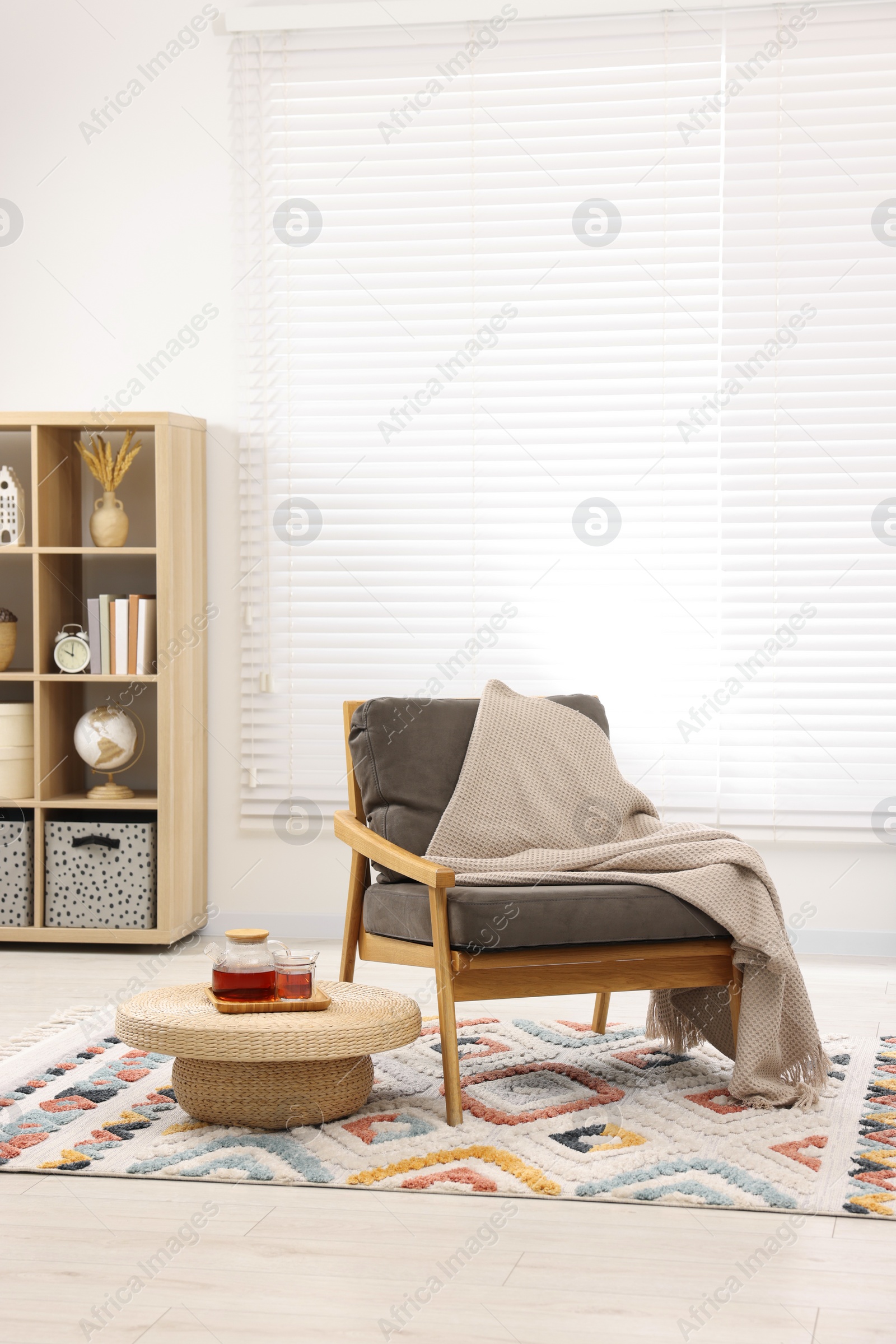 Photo of Stylish living room interior with comfortable armchair, blanket and side table