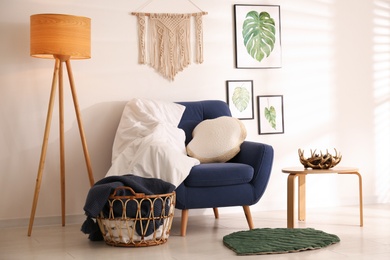 Photo of Stylish room interior with comfortable armchair, blankets and beautiful decor elements