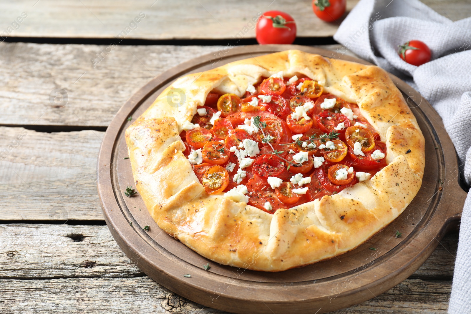 Photo of Tasty galette with tomato, thyme and cheese (Caprese galette) on wooden table, closeup. Space for text