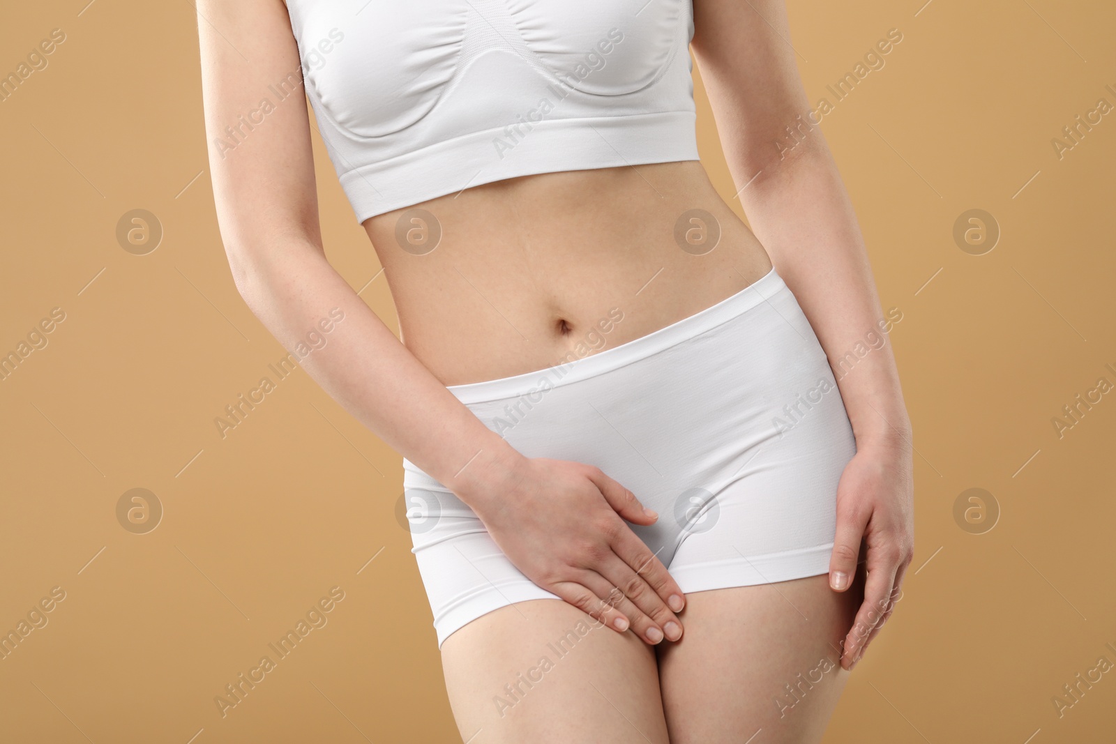 Photo of Woman suffering from cystitis on beige background, closeup