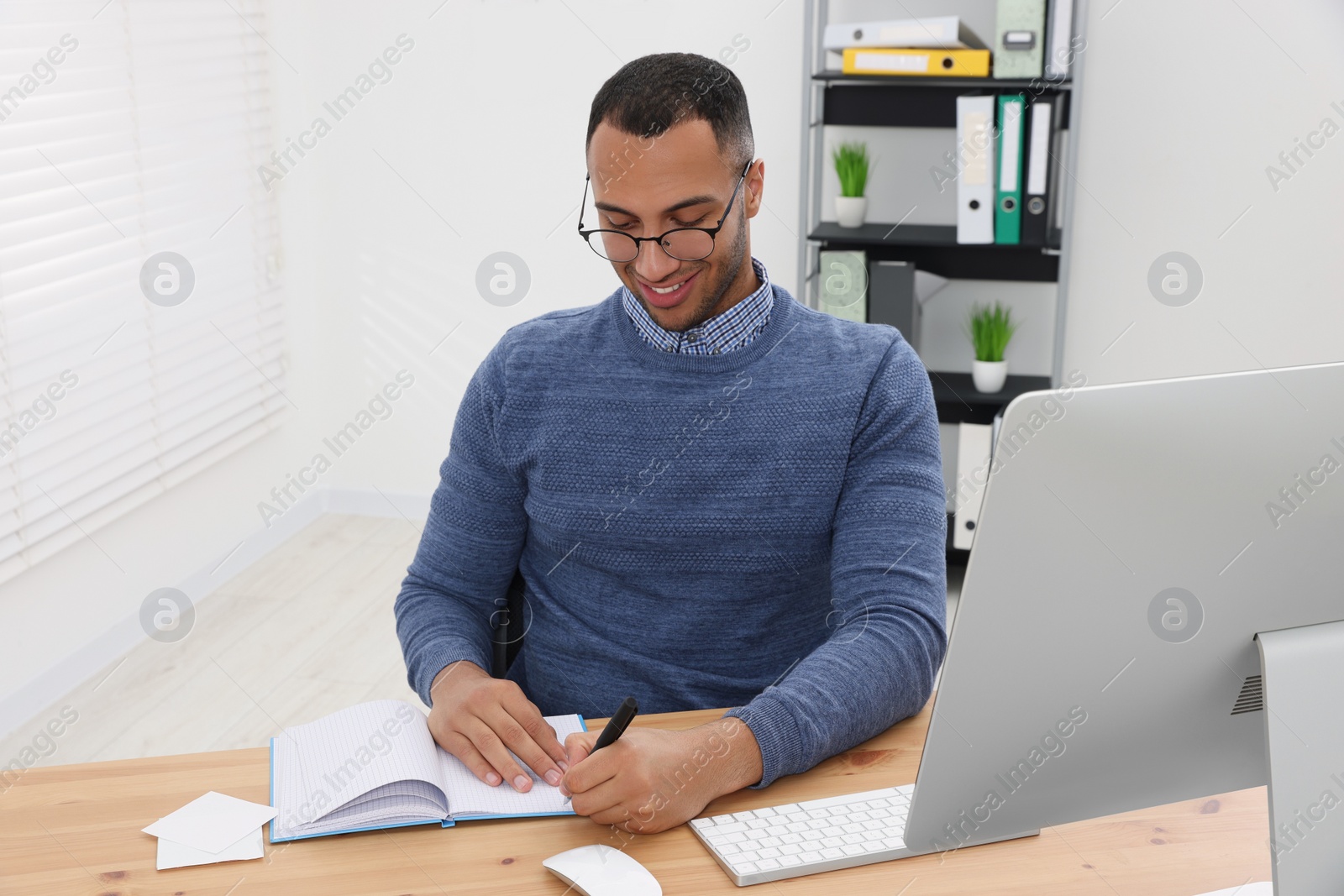 Photo of Happy young intern working at table in modern office