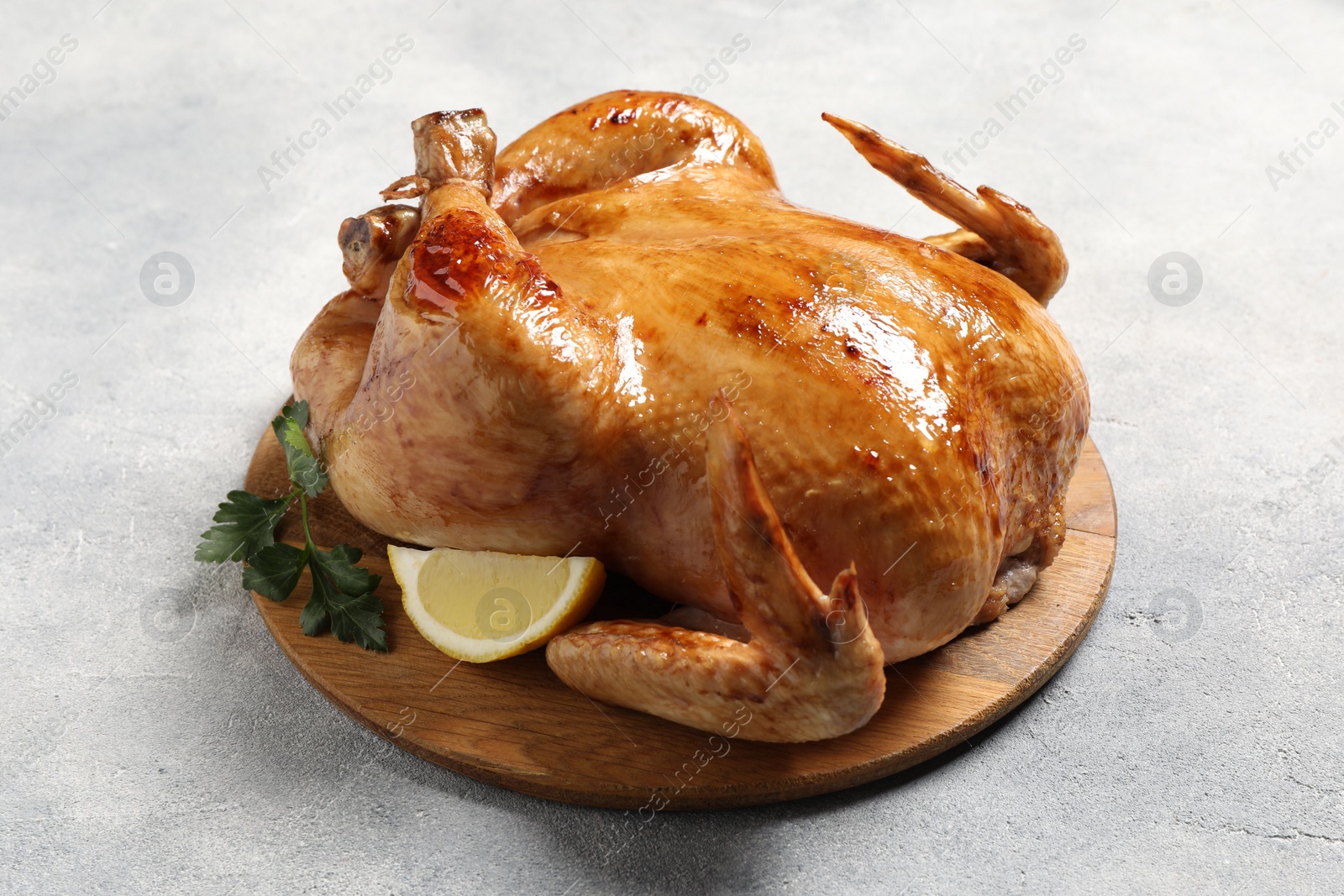 Photo of Tasty roasted chicken with parsley and lemon on light grey table
