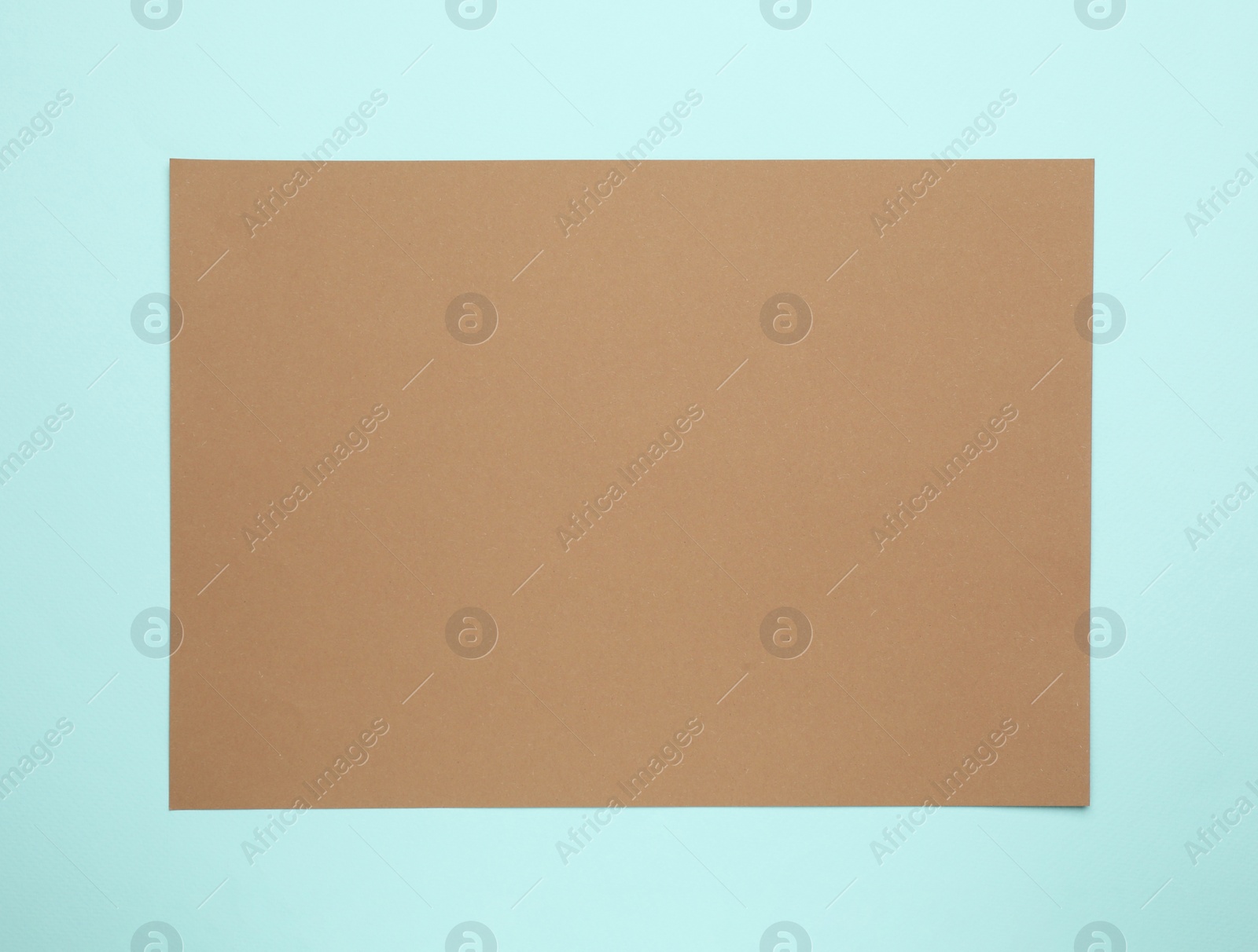 Photo of Sheet of brown paper on light blue background, top view