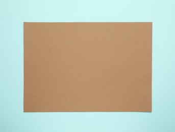 Photo of Sheet of brown paper on light blue background, top view