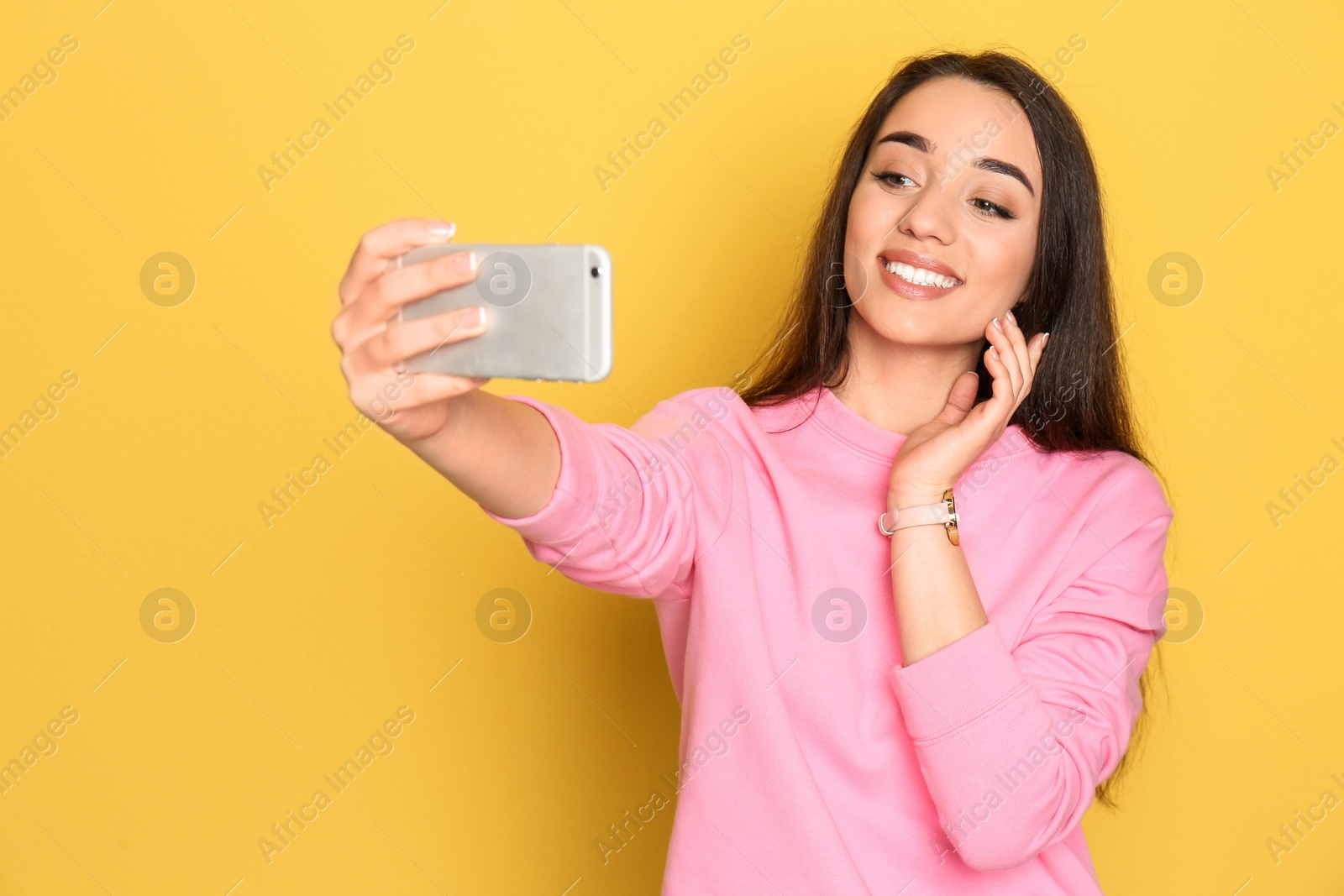 Photo of Young beautiful woman taking selfie against color background