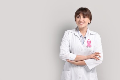 Mammologist with pink ribbon on light grey background, space for text. Breast cancer awareness