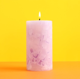 Alight scented wax candle on color background