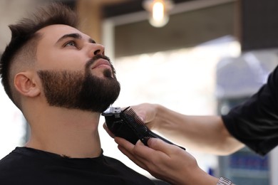 Professional hairdresser working with client in barbershop