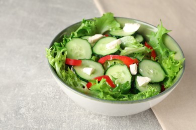 Photo of Delicious salad with cucumbers, red bell pepper and feta cheese in bowl on light grey table, closeup
