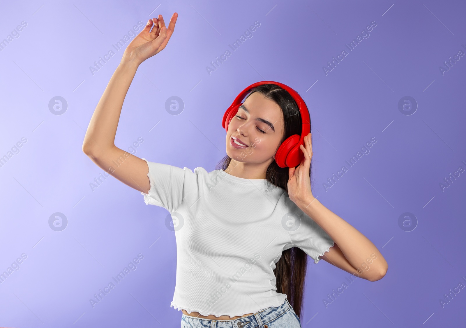 Photo of Teenage girl listening music with headphones on violet background