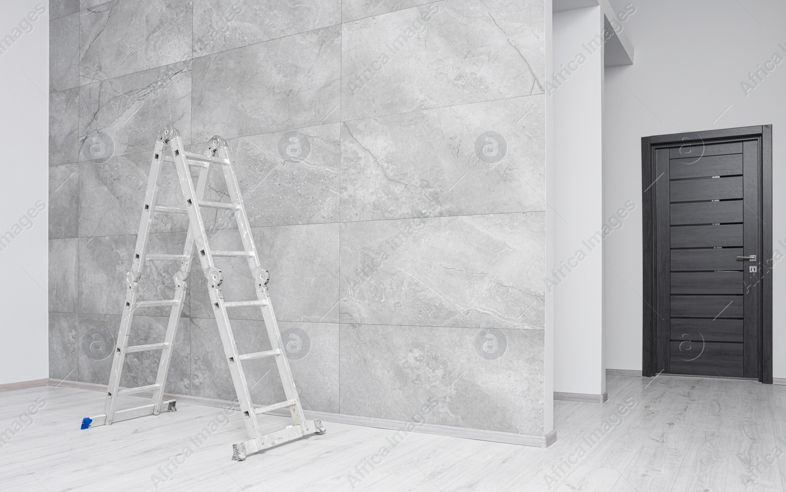 Photo of Empty room with tiled wall and ladder during repair