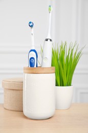 Electric toothbrushes in holder on wooden table