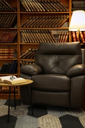 Photo of Cozy home library interior with leather armchair and collectionvintage books on shelves