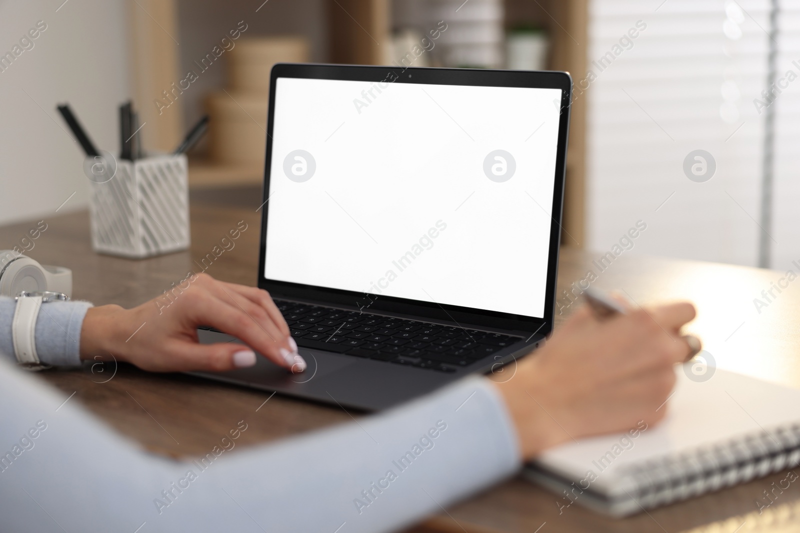 Photo of Young woman writing down notes during webinar at table indoors, closeup