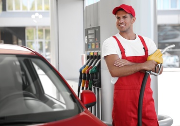 Photo of Worker with fuel pump nozzle near car at modern gas station