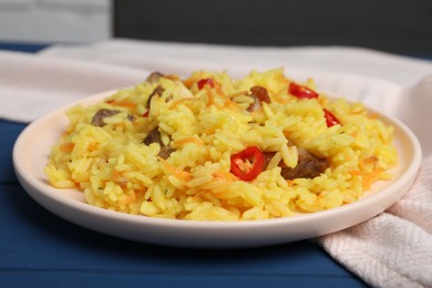 Photo of Delicious pilaf with meat on blue wooden table, closeup