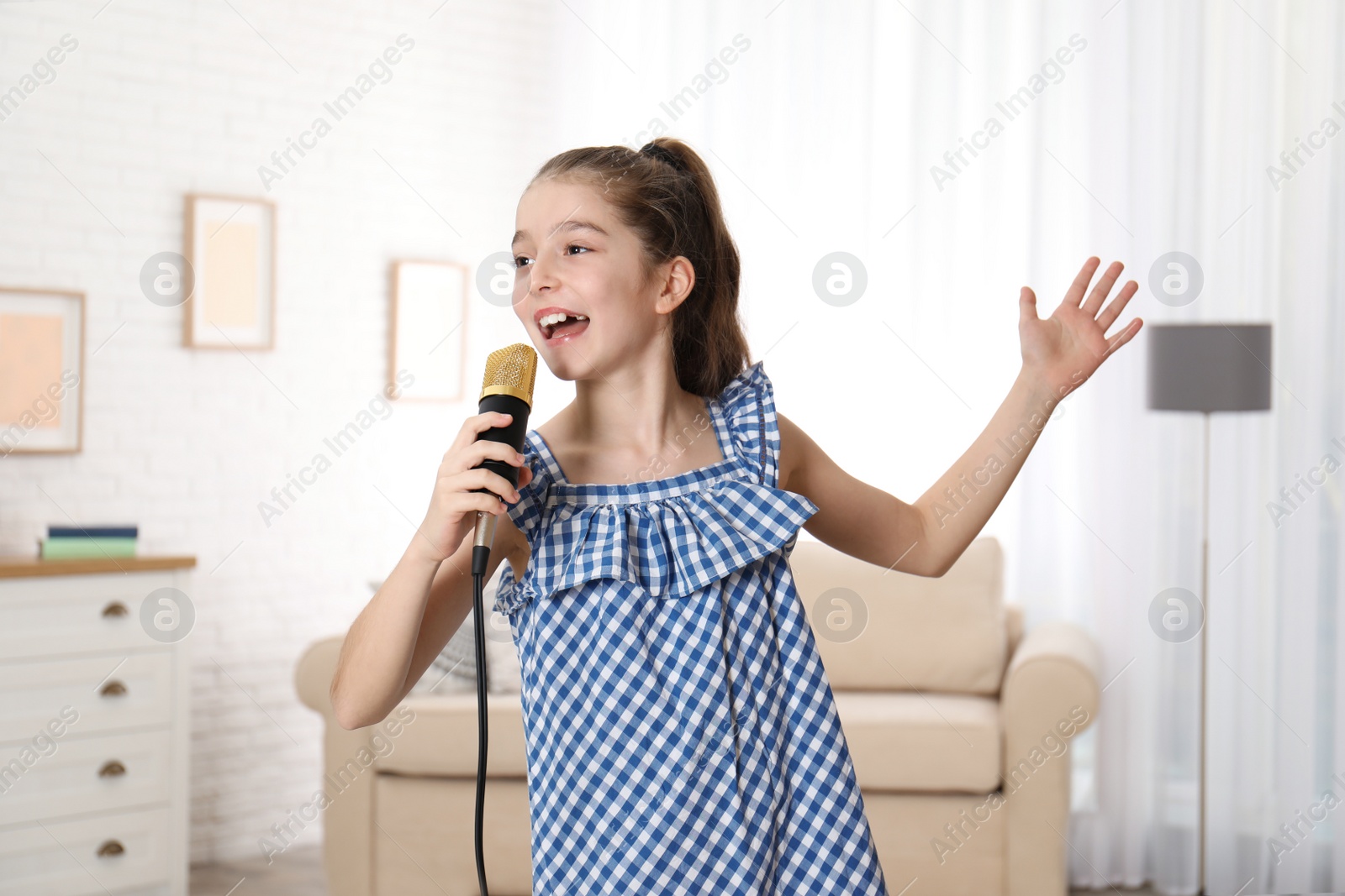 Photo of Cute girl singing in microphone at home