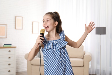 Photo of Cute girl singing in microphone at home