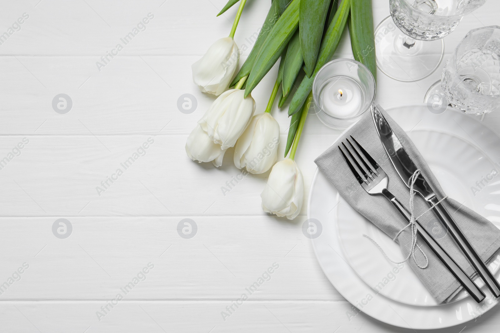 Photo of Stylish setting with cutlery and tulips on white wooden table, flat lay. Space for text